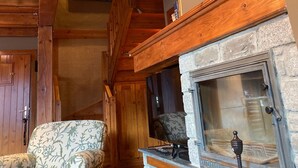 A wooden interior with a stone fireplace, a mounted animal head, and patterned furniture. - Baqueira 3 room, 4 cw spectacular duplex with parking for 6-8 people (Baqueira)