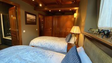 Un dormitorio con dos camas, un armario de madera, una mesita de noche, una lámpara y una ventana con cortinas.