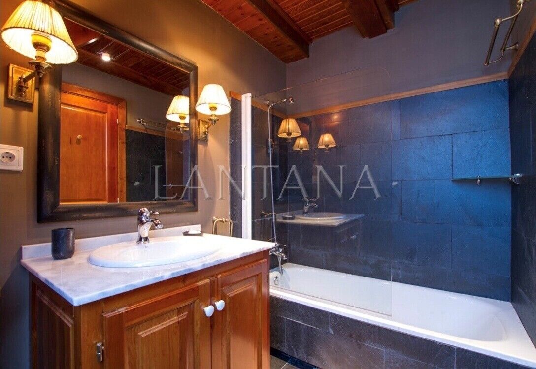 A modern bathroom with a large mirror, two sinks, and a bathtub.
