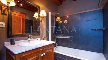 A modern bathroom with a large mirror, two sinks, and a bathtub.