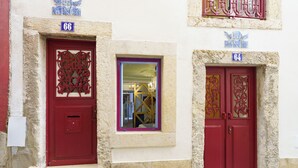 A building with two red doors, each with intricate metalwork, and a small window between them.