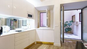 A compact kitchen with white cabinets, a built-in microwave, and a small window.