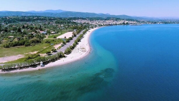 An aerial view of a coastal area with a beach, clear blue waters, and a town in the background. - Beautiful Summer Villa in Chalkoutsi, East Attica (Chalkoutsi)