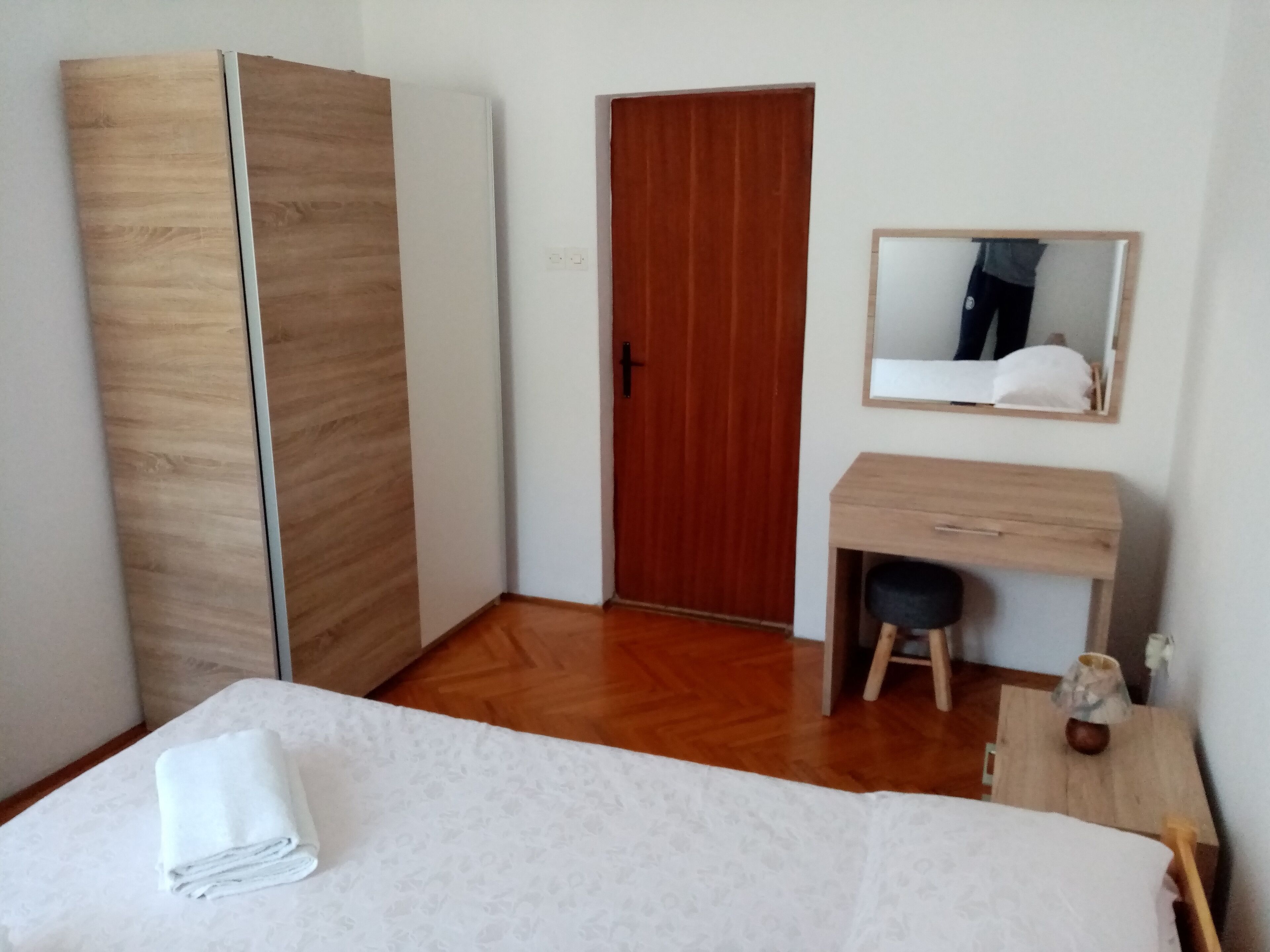 Une chambre à coucher comprenant un lit, une armoire en bois, un bureau avec une chaise et un miroir.