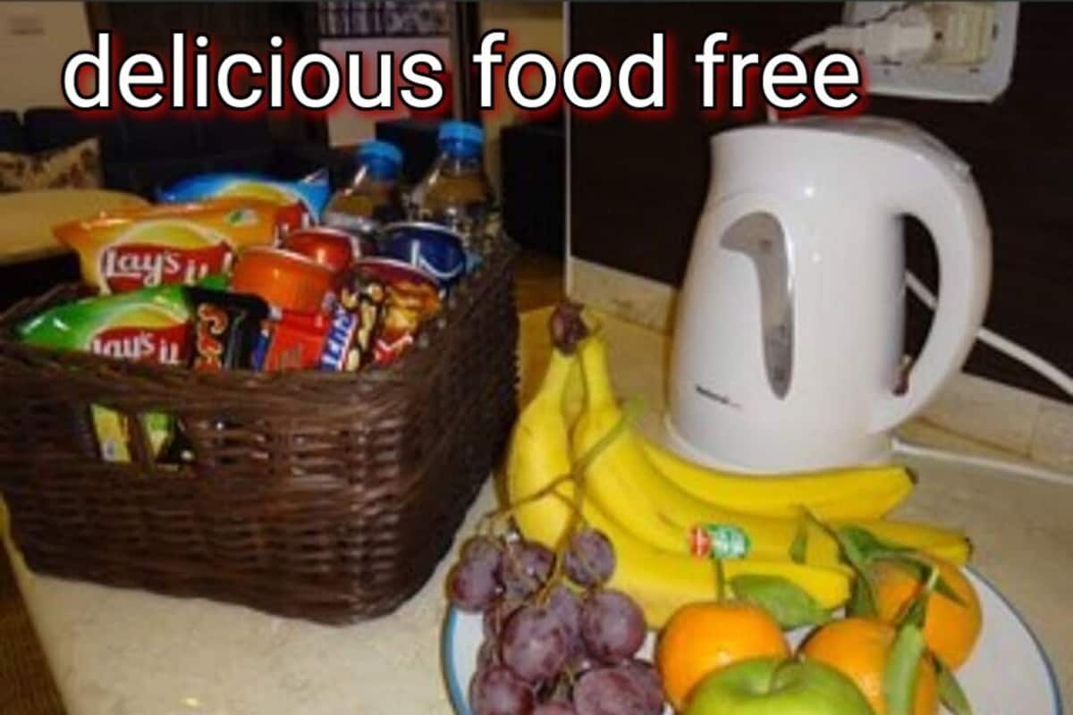A basket of snacks, a plate with fruits, and a white mug on a kitchen counter.