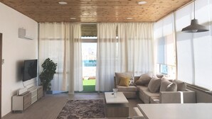 Ett vardagsrum med ett träpanelat tak, en tv, en soffa, ett soffbord och en växt.