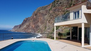 A modern pool with a clear view of the ocean and a rocky hillside in the background. - 3 bedroom villa and pool, Jardim do Mar, breathtaking view  (Jardim do Mar)