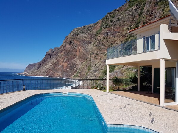 A modern pool with a clear view of the ocean and a rocky hillside in the background. - 3 bedroom villa and pool, Jardim do Mar, breathtaking view (Jardim do Mar)