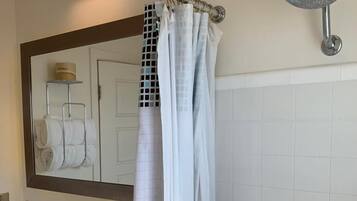 A bathroom with a white toilet, a sink, a mirror, and a shower with a curtain.