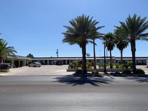 A parking lot with palm trees and a building in the background. - The Sands Motel (Boulder City)
