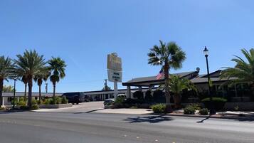 A hotel with a clear sky, palm trees, and a signboard.