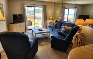 A living room with a sofa, armchairs, a coffee table, and a TV. - 111 - Poolside 1 bedroom closest to the water (New Smyrna Beach)