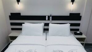 A double bed with white linens and two pillows, a bedside table with a phone and a box, and wall-mounted lights. - Infinity Dhiffushi (Dhiffushi)