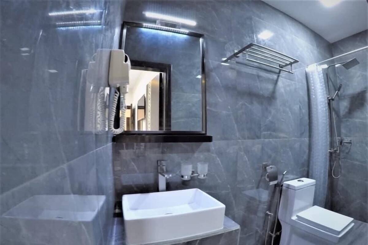 A modern bathroom with a large mirror, a sink, a toilet, and a shower area.
