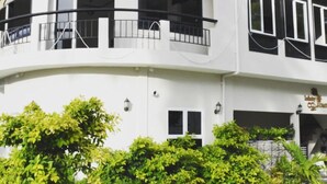 A two-story building with a white facade, balconies with black railings, and a blue roof. - Infinity Dhiffushi (Dhiffushi)