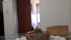 Une pièce avec une table en verre, un chemin de table à motifs, un cactus et une tête de lit en bois.