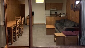 Un ambiente compatto con angolo ristoro, divano e angolo cottura.