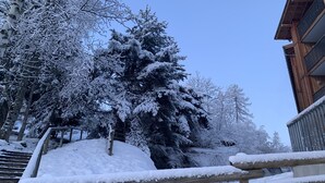 Una scala di legno conduce a un edificio circondato da alberi innevati.