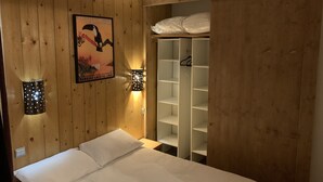 Una stanza con rivestimenti in legno, un letto, un poster e un armadio con scaffali.