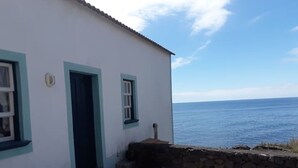 A coastal building with a stone wall and a door, overlooking the sea.