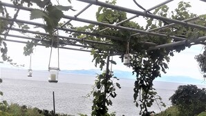 A pergola with hanging lanterns overlooking a body of water.