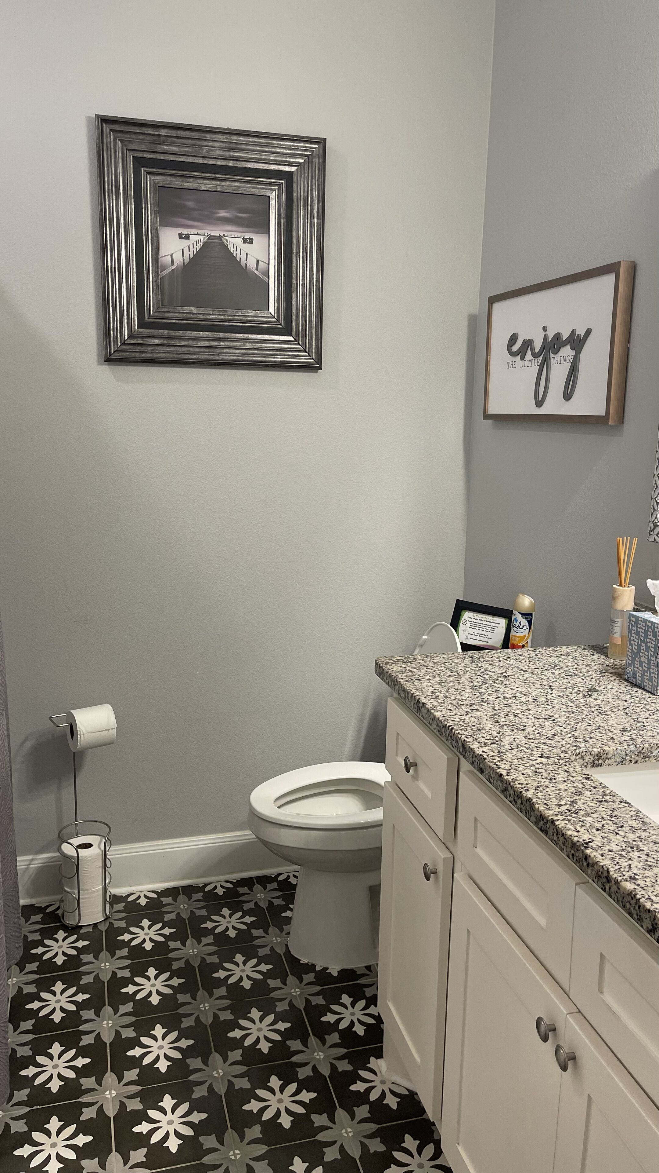 A bathroom with a toilet, sink, and decorative wall art.