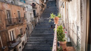Un escalier étroit dans un bâtiment historique, doté de balcons et agrémenté de plantes en pot.