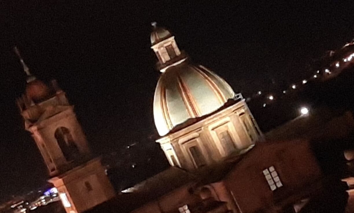 Vista nocturna de un edificio con una cúpula destacada y una torre.