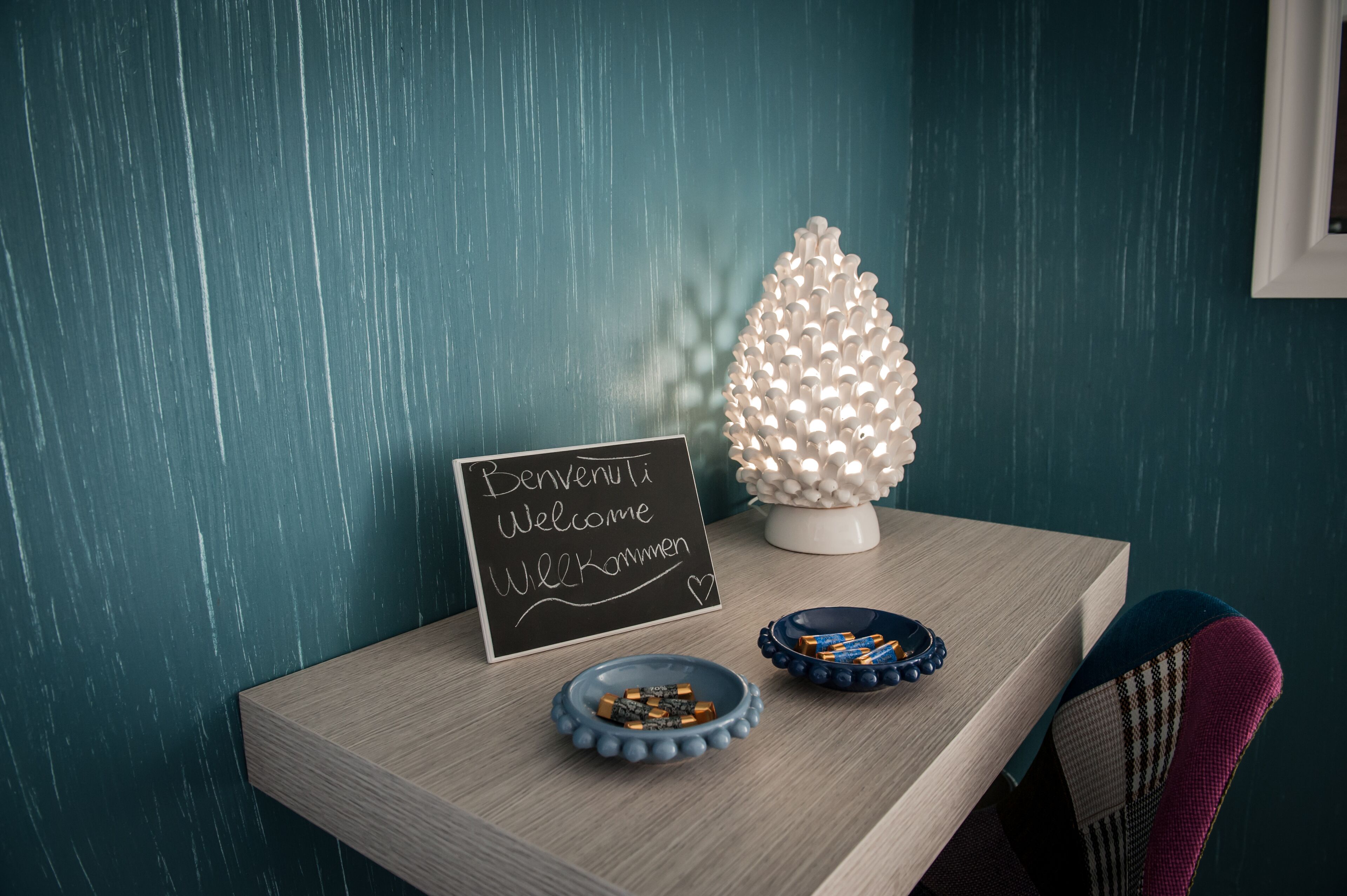 Uma mesa de madeira com um quadro negro, uma árvore decorativa e duas taças de chocolate.