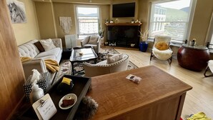 A living room with a sofa, armchairs, a coffee table, a fireplace, and a TV mounted on the wall. - Great View! Wilma Building - Downtown Missoula (Missoula)