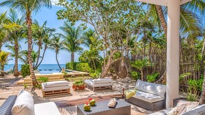Un'area relax esterna tropicale con diverse opzioni di posti a sedere, una piscina e vista sull'oceano.