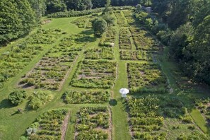An aerial view of a garden with neatly arranged plots and a central gazebo. - Log Cabin w/ Amazing Views, River Frontage & Hot Tub (Newfane)