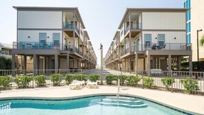 A modern hotel with a central pool, balconies, and a symmetrical design. - Short walk to Beach - Pool -Sleeps 8 Wifi (Gulf Shores)