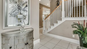 Un intérieur moderne avec un escalier, une console agrémentée d’objets décoratifs et un grand tableau abstrait.