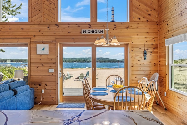 Una cabaña de madera con vistas a la playa, una mesa de comedor con sillas y un cartel que dice 'Michigan'.