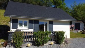 A single-story house with a dark roof, white siding, and a front porch with a wooden railing. - HOLIDAY IN QUIET AT THE MOUNTAIN (Issor)
