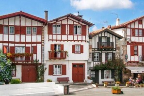 A traditional European building with a white facade and red timber framing. It features a balcony with flowers and a visible café named "CAFE EZKURRA" in the foreground. - HOLIDAY IN QUIET AT THE MOUNTAIN (Issor)