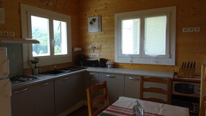 A compact kitchen with wooden walls, a gas stove, a sink, and a microwave. - HOLIDAY IN QUIET AT THE MOUNTAIN (Issor)