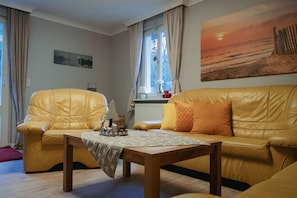 A living room with a yellow leather sofa, a wooden coffee table, and a painting of a sunset.