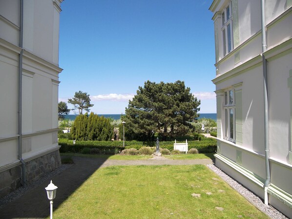 A courtyard with a lawn, a statue, and a view of the sea.