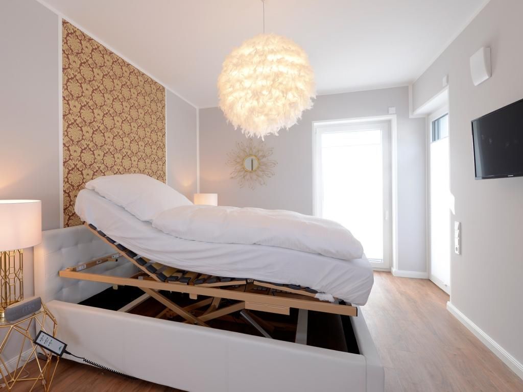 Een slaapkamer met een bed, een wandtelevisie en een hanglamp.