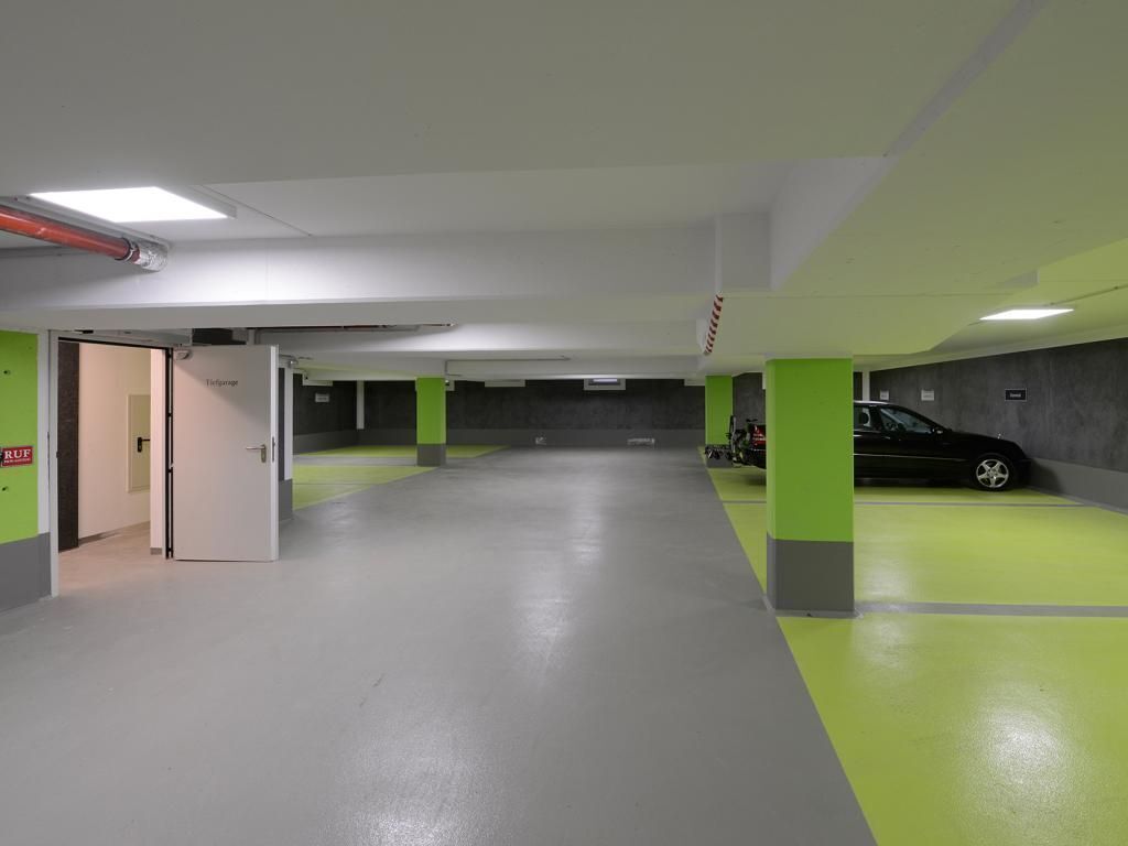 A parking garage with green pillars, a white door, and a black car parked.