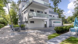 A modern multi-story building with a flat roof, large windows, and a balcony. - Tide App. 3 gold right (Ostseebad Boltenhagen)