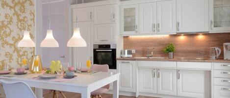 A modern kitchen with white cabinets, a wooden countertop, and pendant lighting.