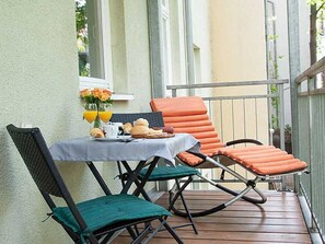 A small outdoor patio with a table set for two, two chairs, and a railing.
