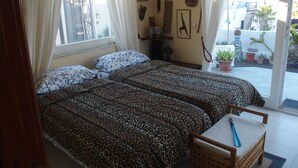 Una habitación con dos camas, una silla y una ventana con cortinas.