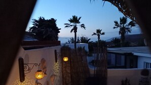 Un patio con una mesa redonda, un aplique de pared y una pared decorativa con la silueta de una palmera.