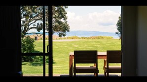 An open door with a view of a grassy field, a tree, and distant mountains. - Comfort Inn Sunset (Thames)