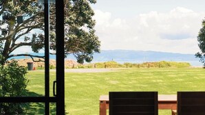 An open door with a view of a grassy field, a tree, and distant mountains. - Comfort Inn Sunset (Thames)