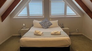 A bedroom with a bed, two bedside tables, a lamp, and a window with blinds. - Comfort Inn Sunset (Thames)